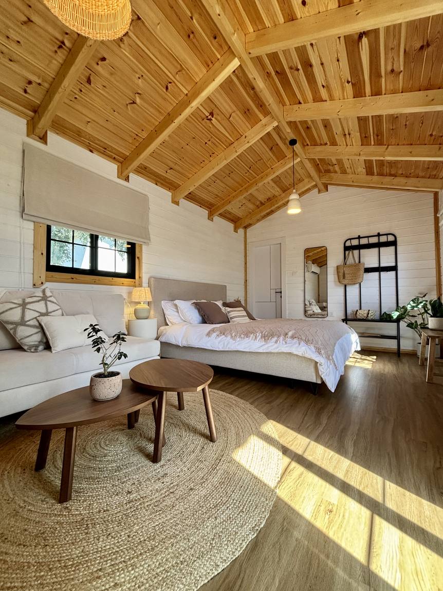 The bright cabin interior: wooden ceiling, sofa, coffee tables and a double bed